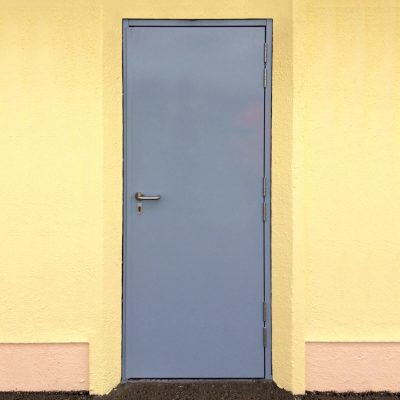 Blue steel door installed in a yellow building