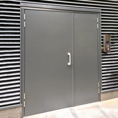 Grey double steel door installed on a building unit with D handle