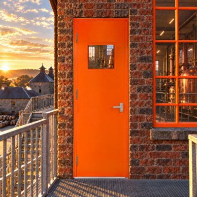 A bright orange Custom Made Fire Exit Door fitted with an OAD in a distillery