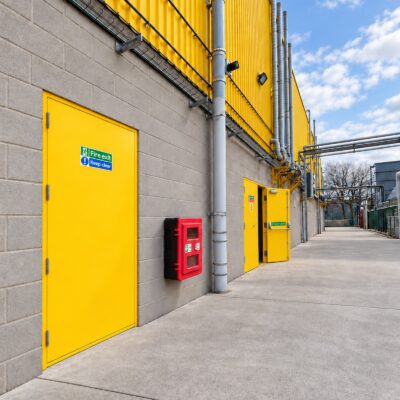 Two traffic yellow Custom Made Fire Exit Doors installed in a factory setting.
