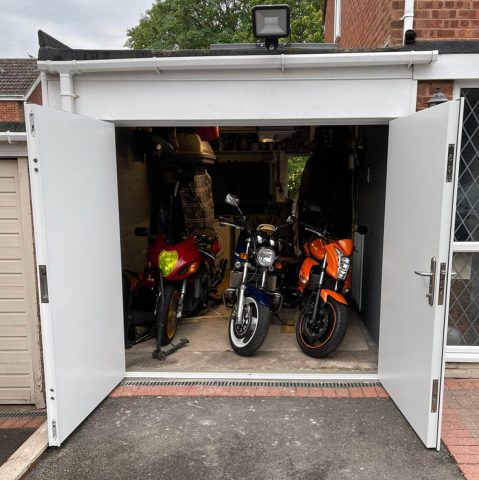 Side hinged garage door open with motorbikes