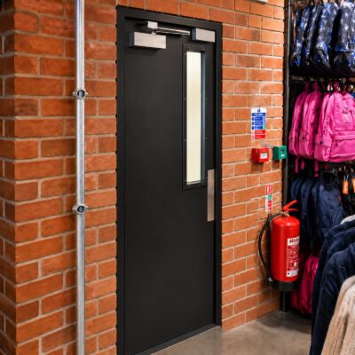 A black blank door with a vision panel installed in a retail environment