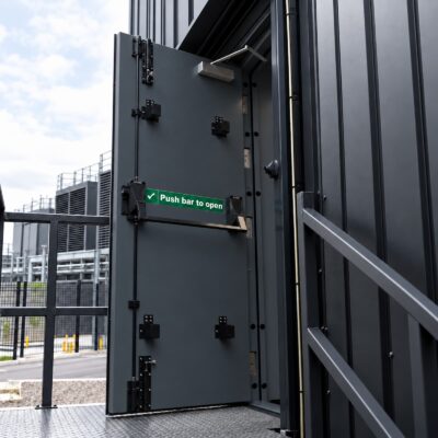 A grey high security fire exit door with drop bar kit